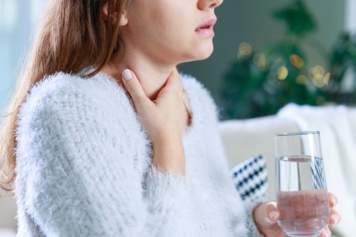 woman grabbing her throat as she struggles from chronic chronic hoarseness